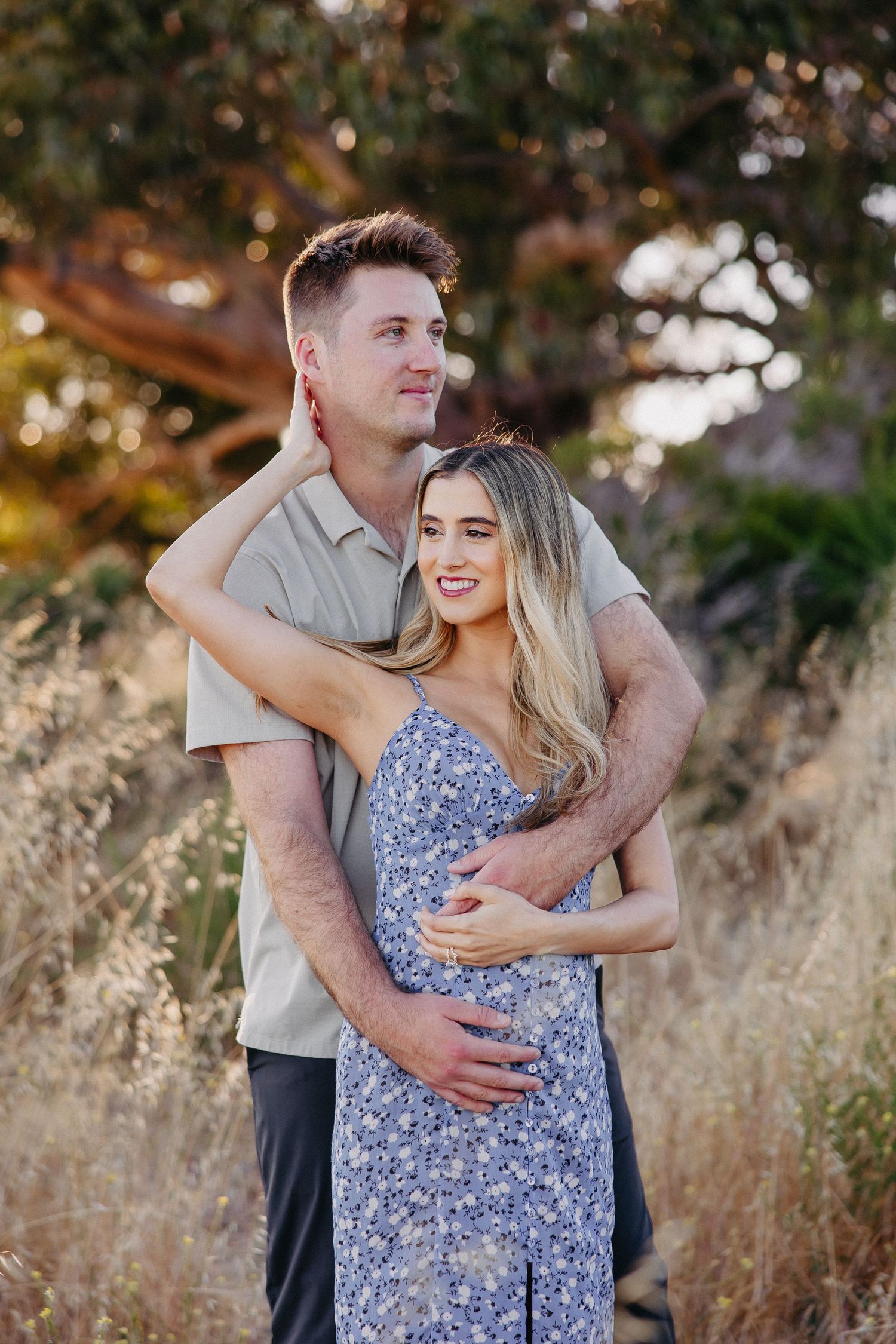Couple shares joyful moment in casual attire among tall grasses at sunset.