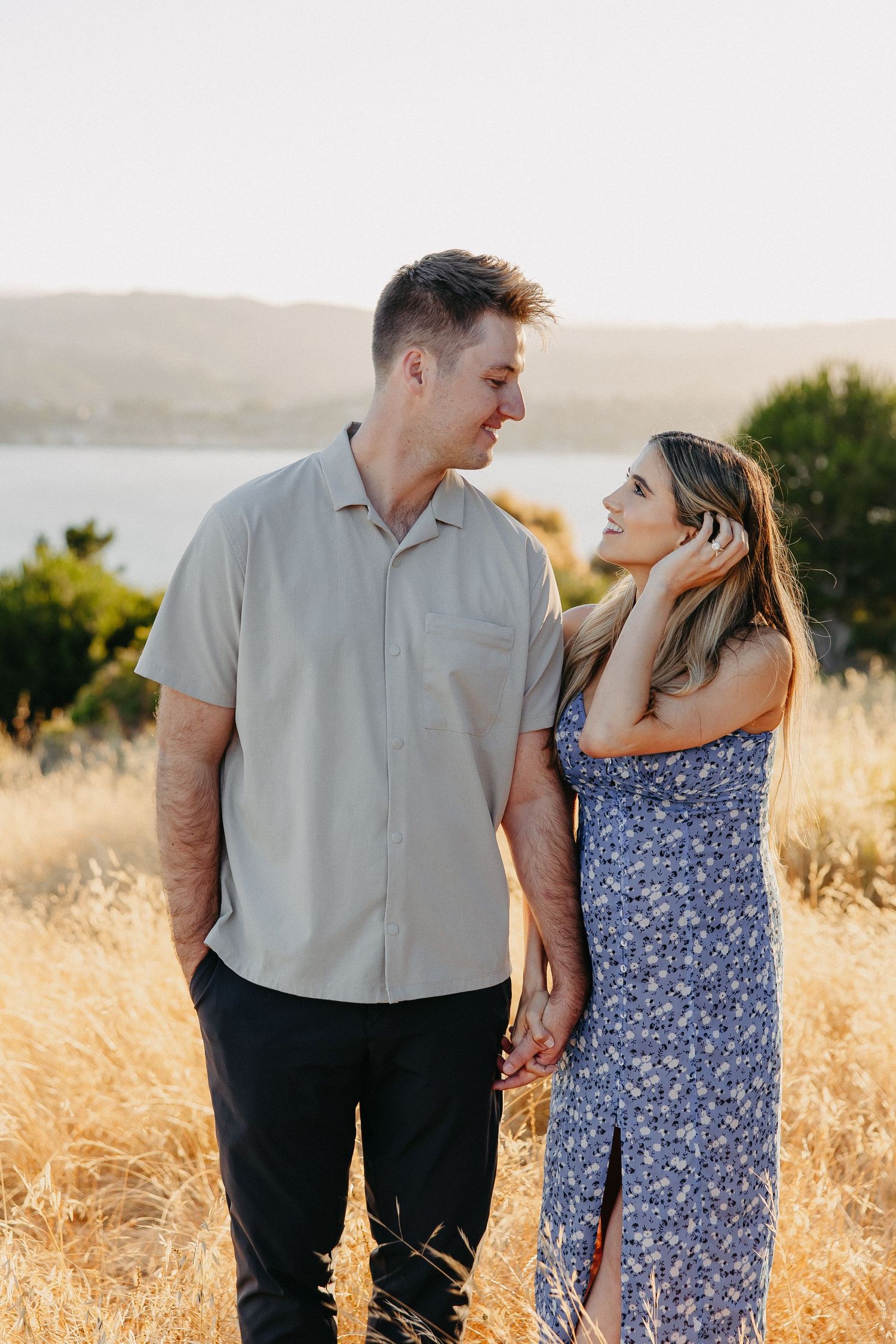 Loving couple gazing at each other in summer field during sunset.