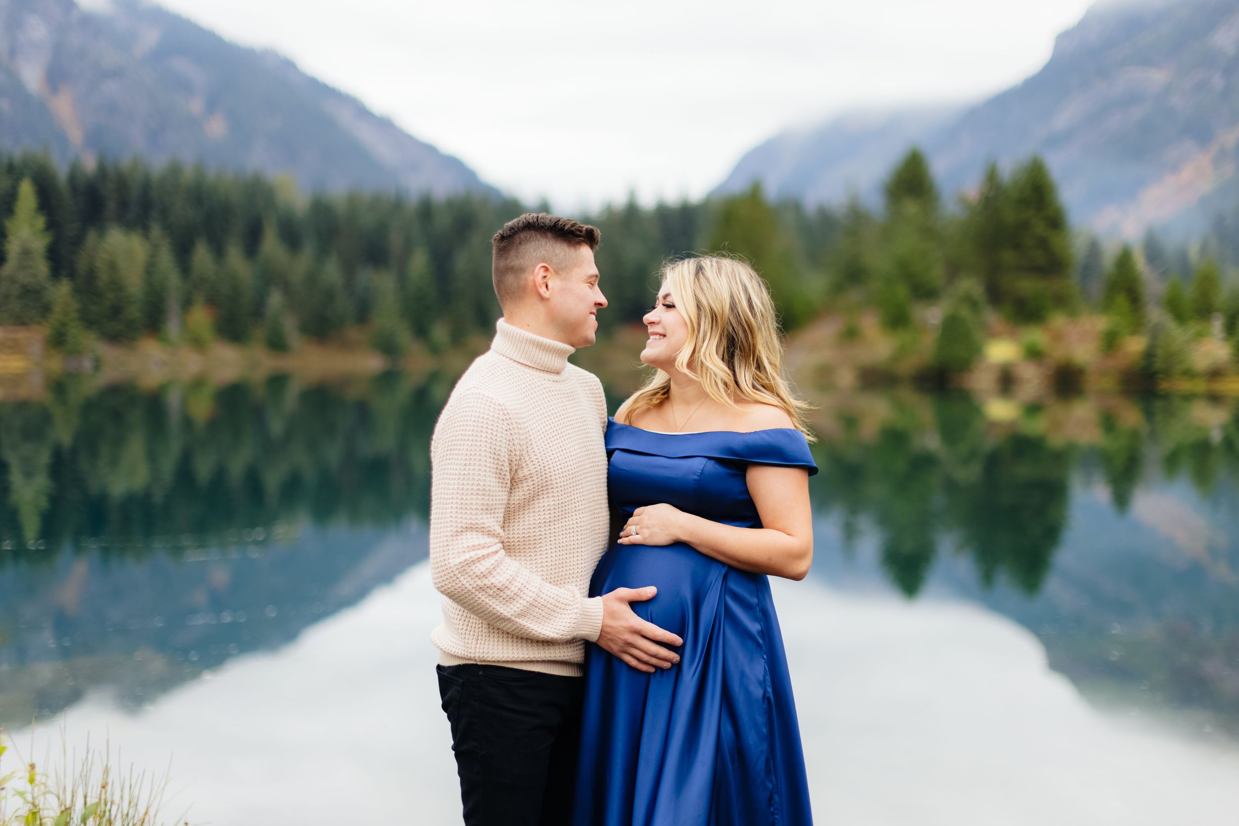 A couple shares an intimate moment by a serene mountain lake.