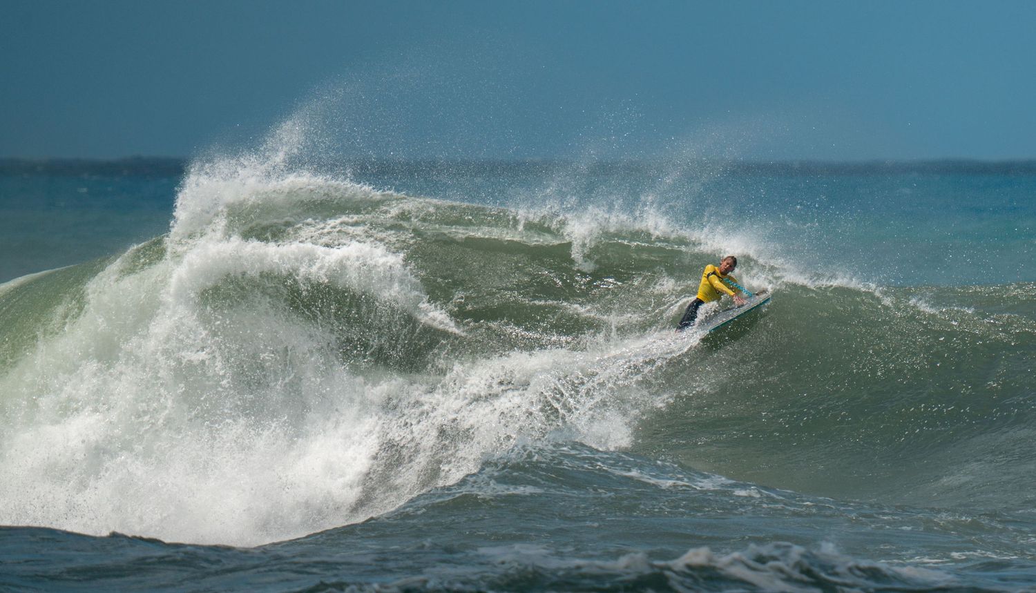 Surfer riding large ocean waves with dynamic water spray in action sequence.