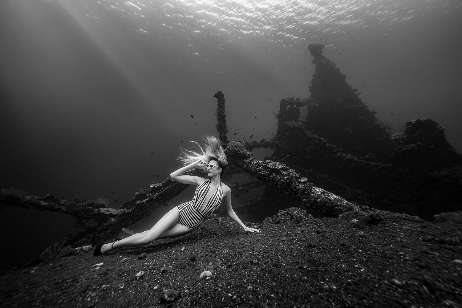 Artistic black and white underwater photo near ancient shipwreck ruins.