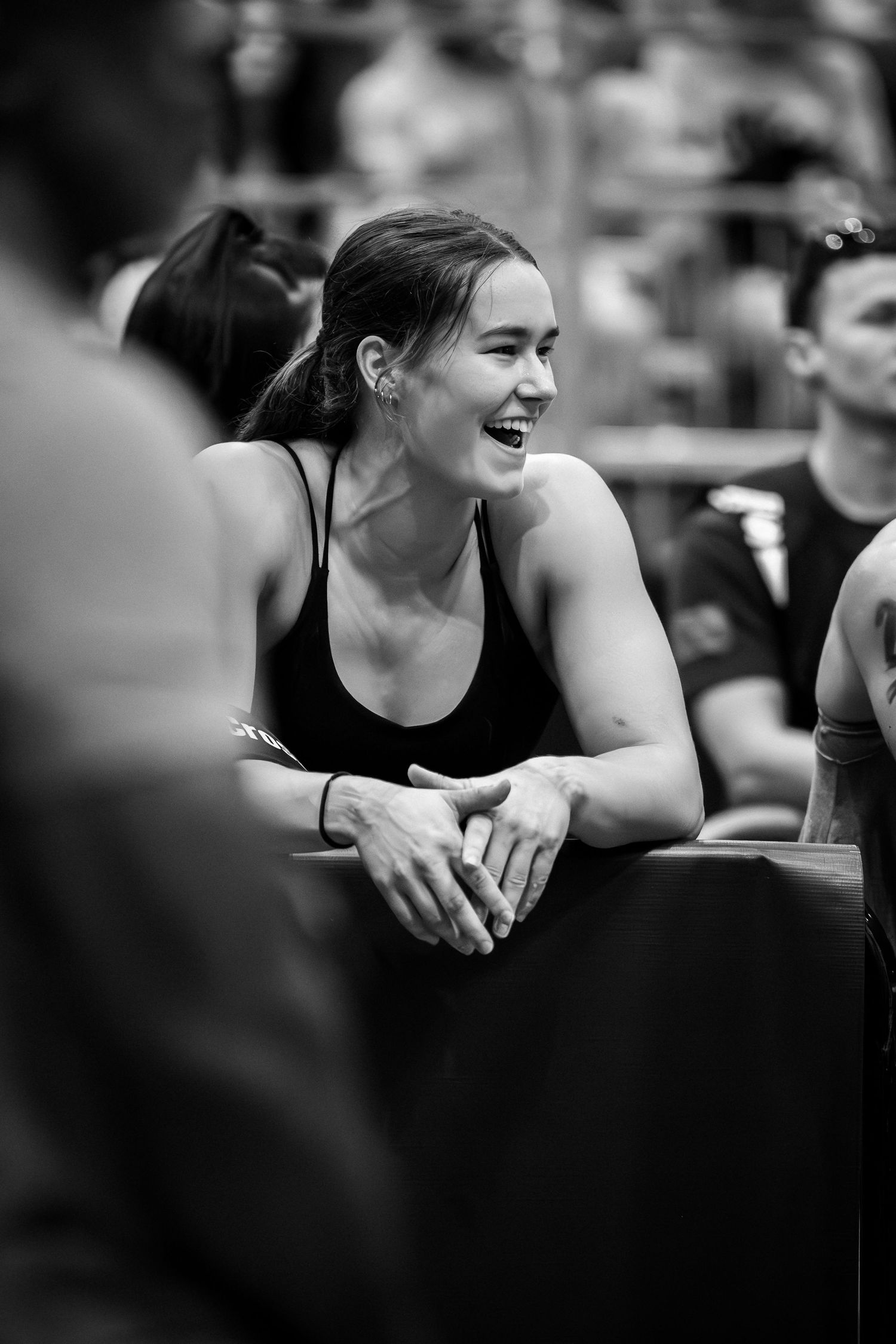Athlete smiling and resting on barrier during competitive fitness event.