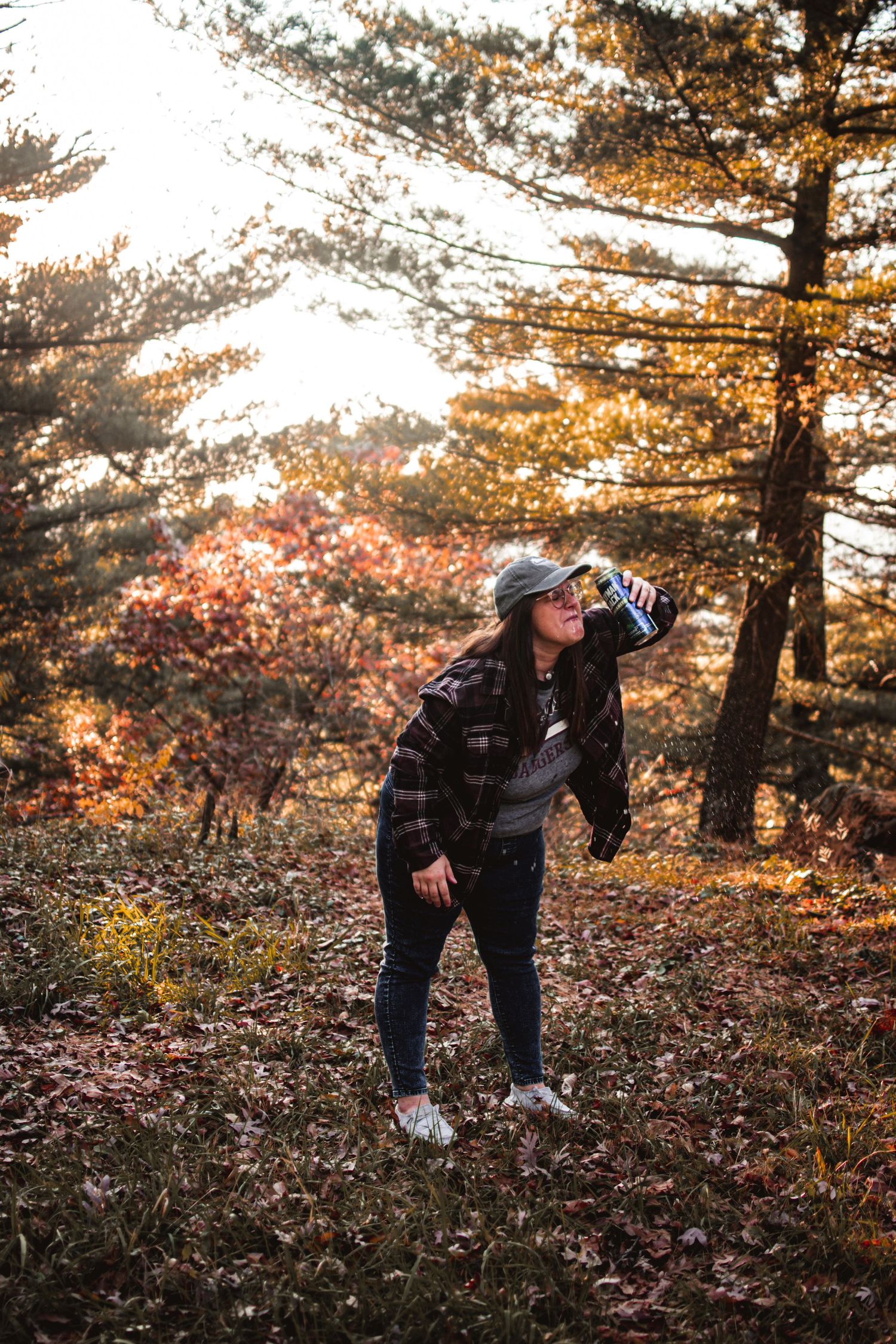 Person in dark clothing exploring autumn forest during golden hour.