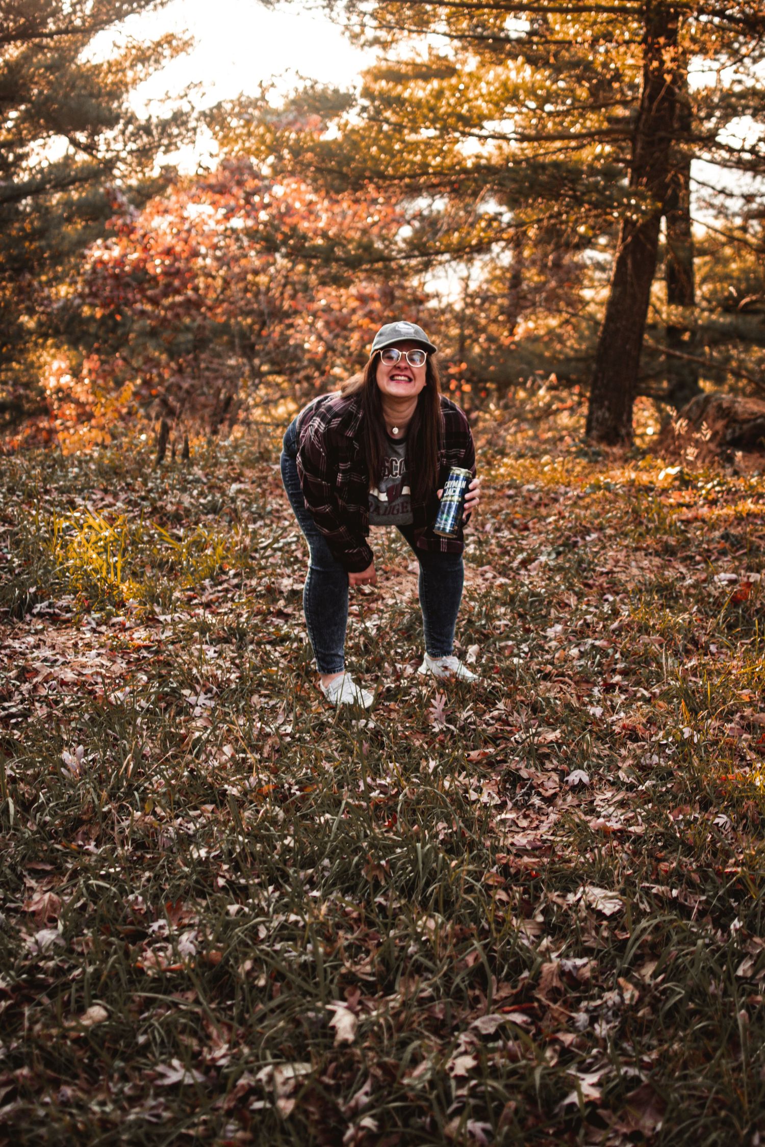 Person in casual wear enjoying autumn scenery in a forest setting.