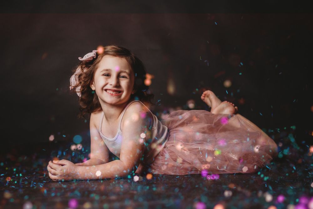 Colorful glitter and confetti scattered across a dark background in a whimsical photo series.