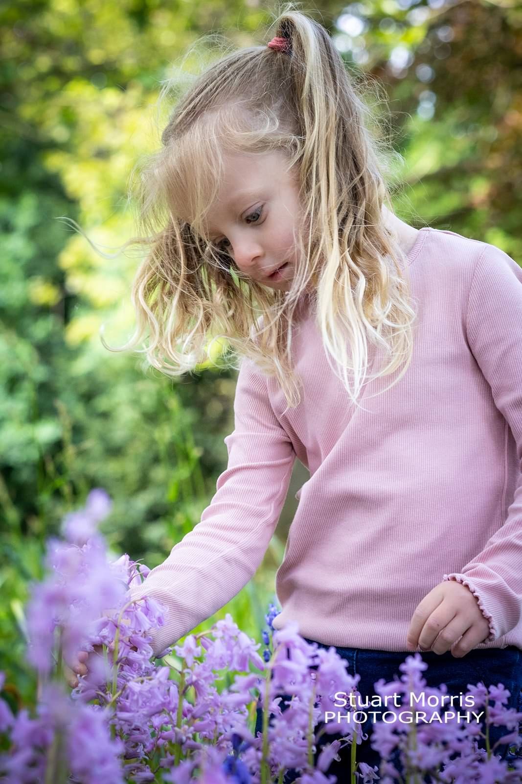 older sister touches the bluenbells in woodlands. outdoor mini portrait session. Stuart Morris Photography.