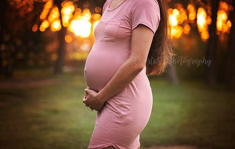 A maternity photoshoot at sunset with warm golden lighting.