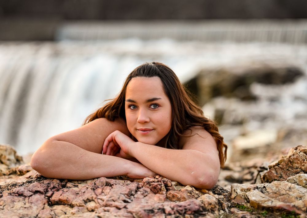 Senior girl laying on a rock by a waterfall