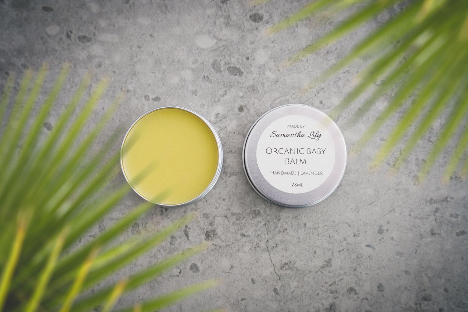 Natural skincare products displayed with palm fronds on concrete background.