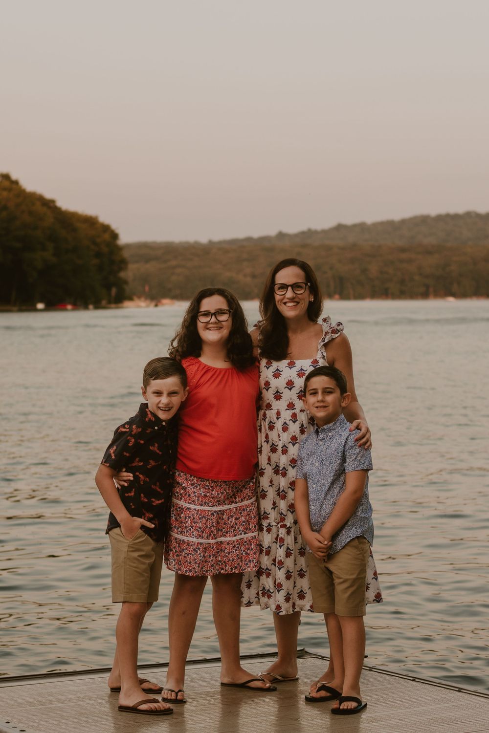 Family group poses casually together on dock during sunset lakeside photoshoot.