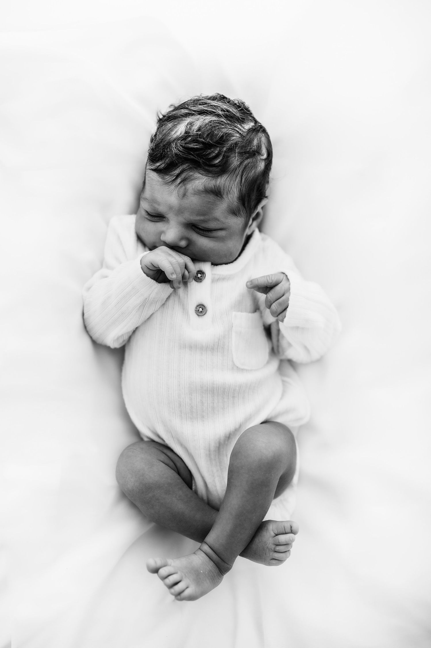 Black and white image of a newborn baby boy laying on a beanbag