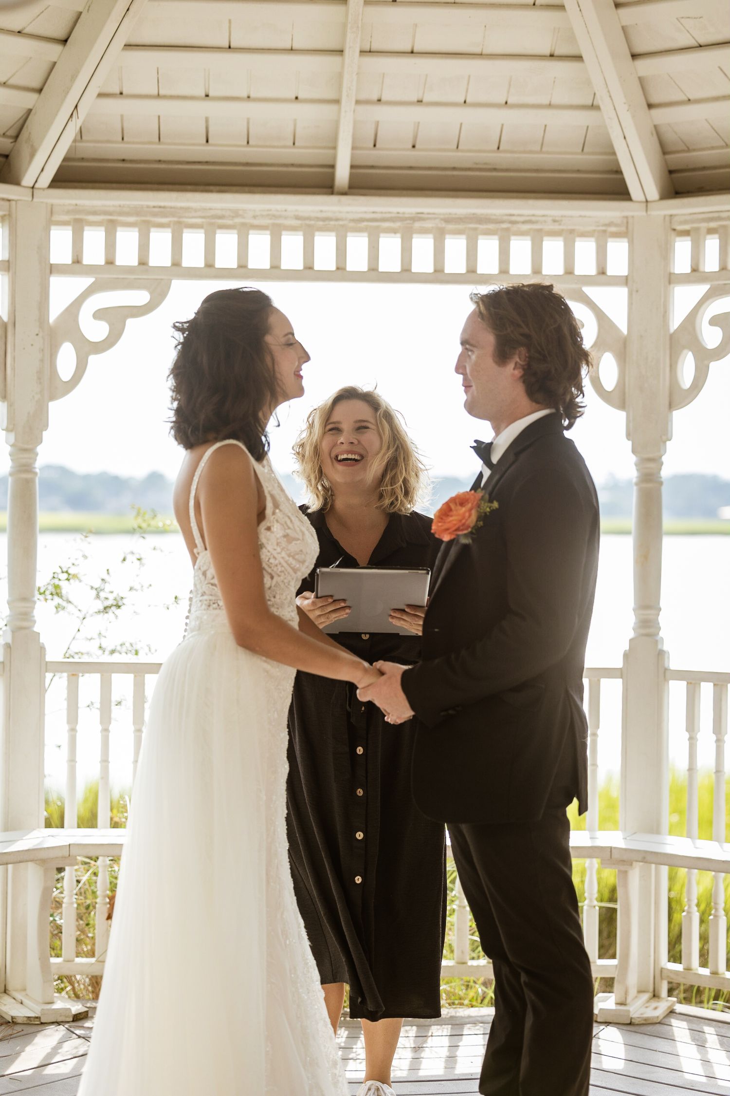 The smiles and laughter of an officiant marrying a bride and groom on the marsh in the Landings, Skidaway Island, Ga.