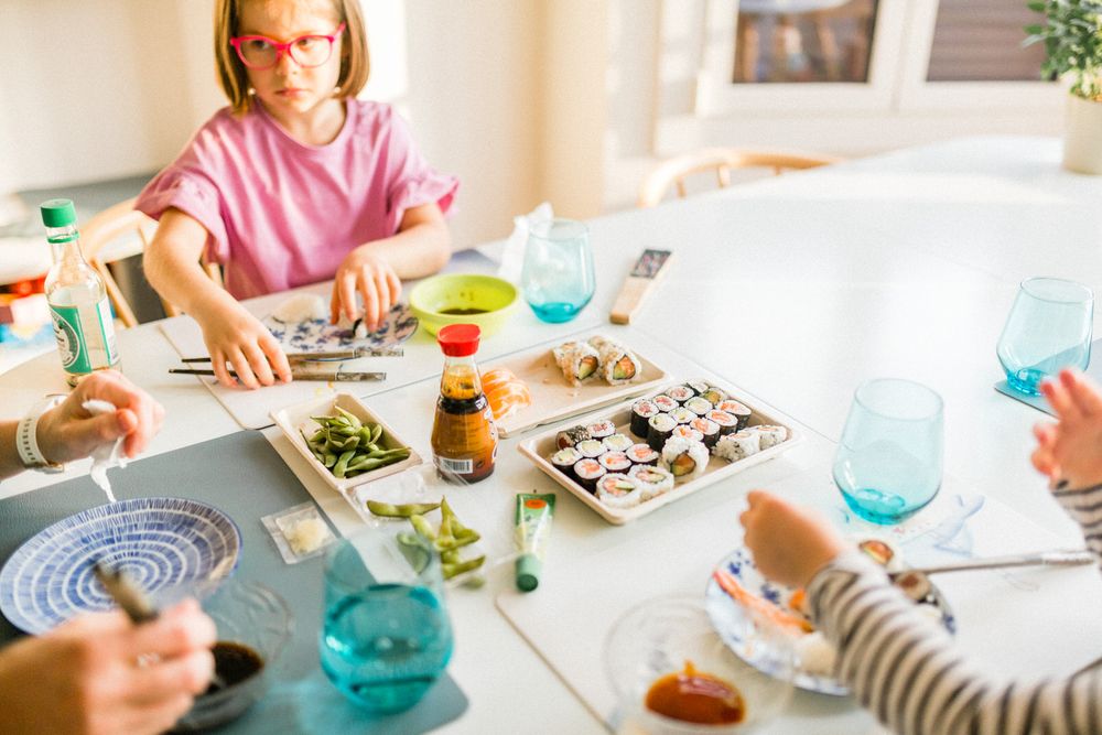 Casual dining scene with colorful drinks and sushi platters on white table.