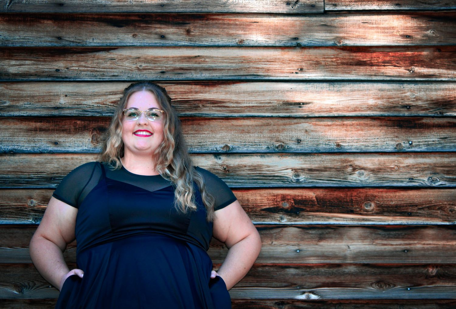 Stylish black dress fashion photo against rustic wooden wall background.