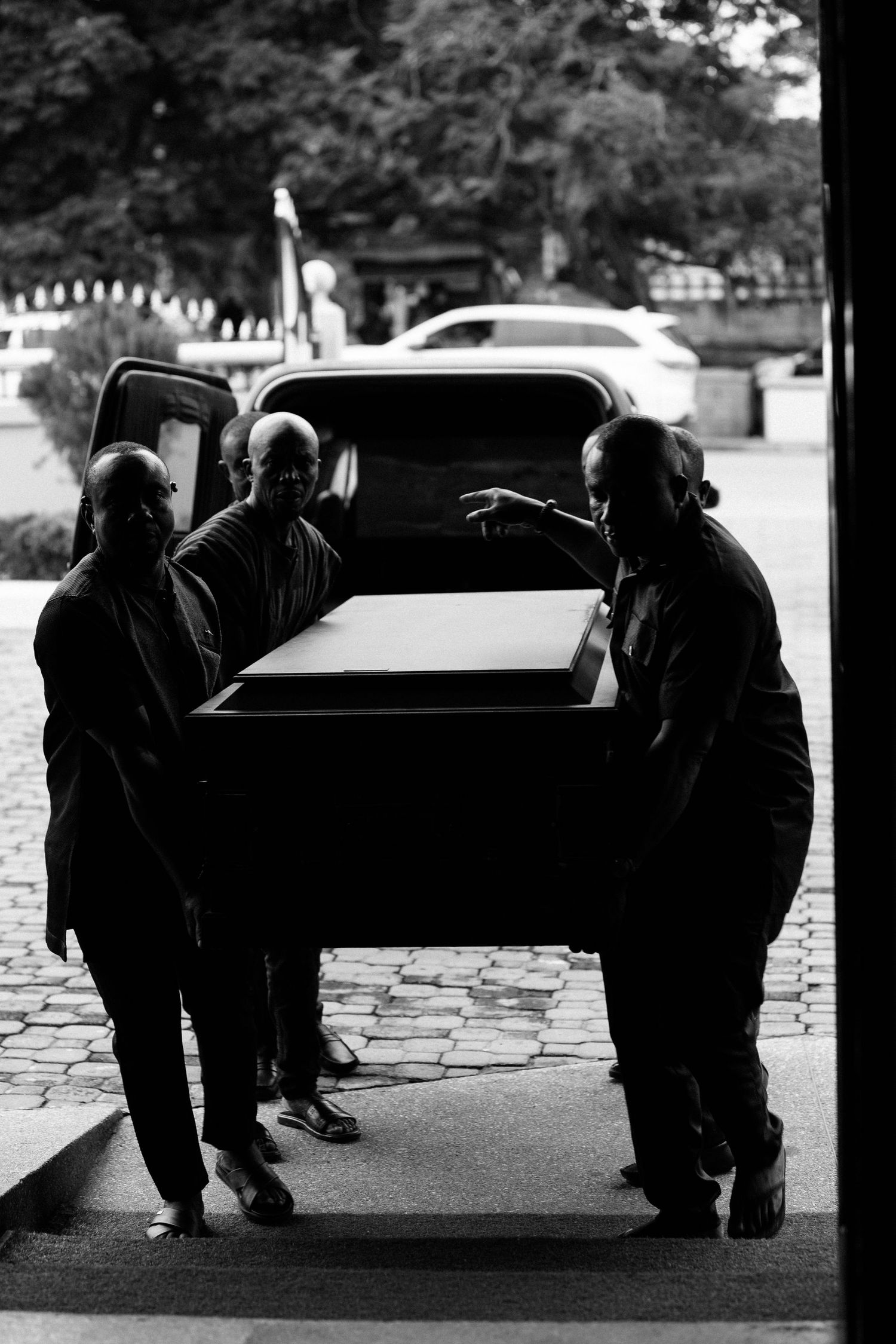 Black and white photo of pallbearers carrying a casket during a funeral procession.