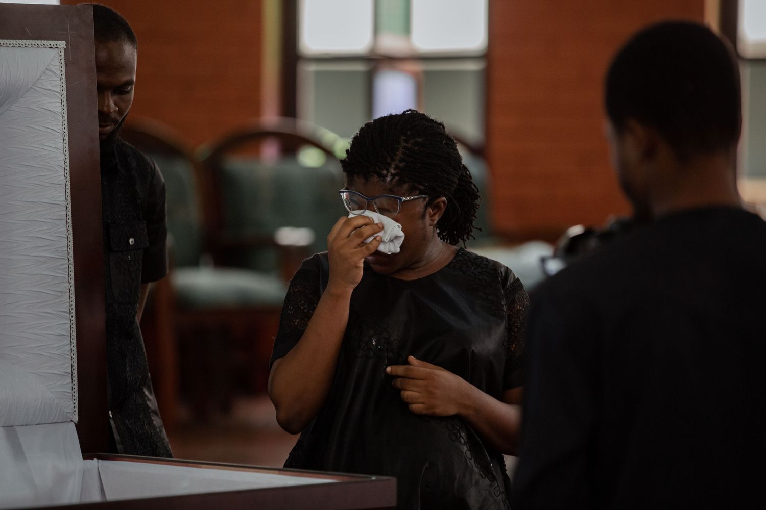 Close-up of family members in black funeral attire standing together in a moment of reflection