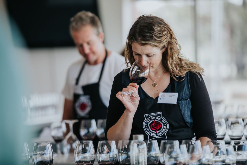 Wine tasting event with multiple glasses being examined by participants.