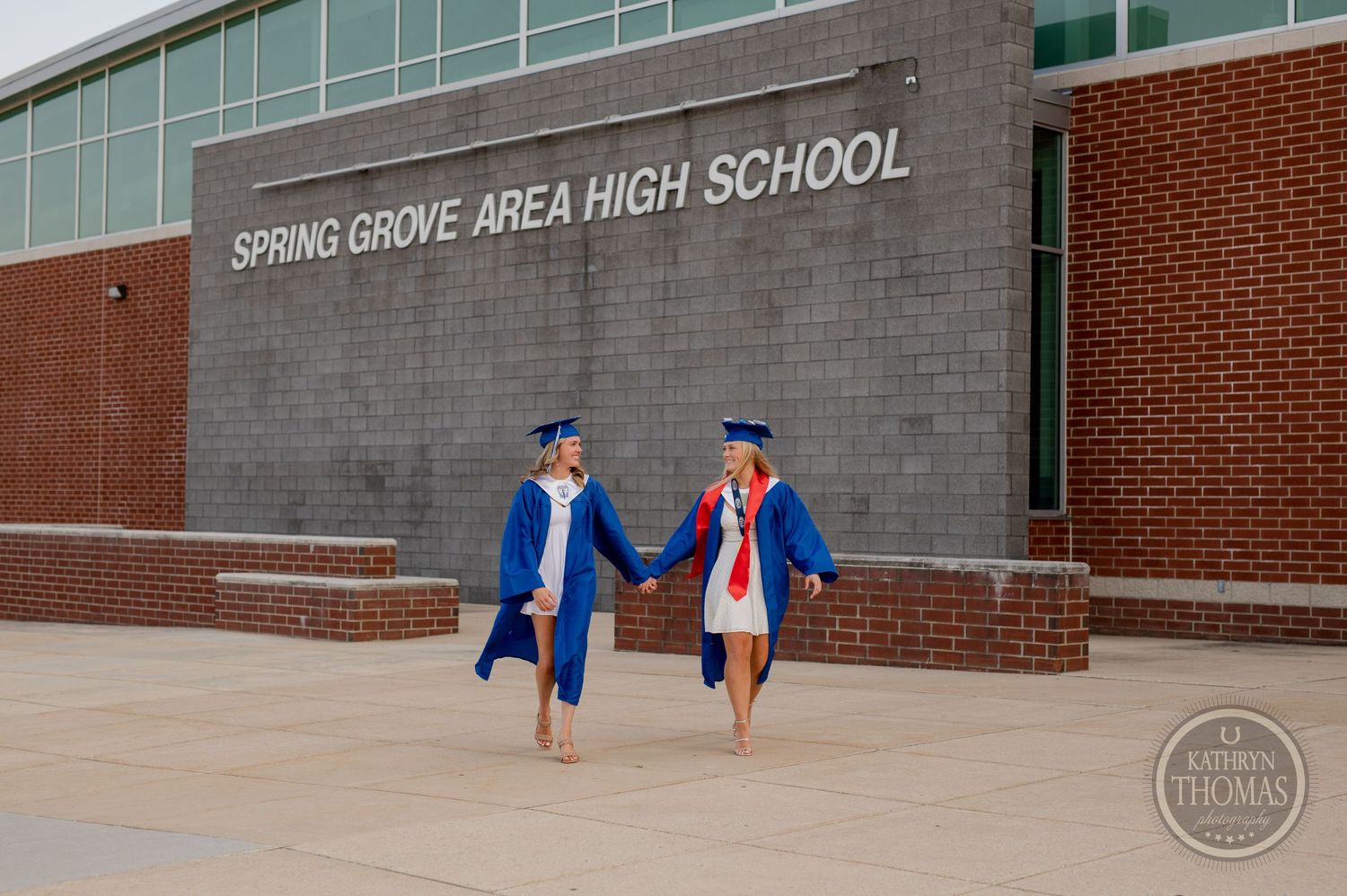 Graduates walking together outside Spring Grove Area High School in blue graduation attire.
