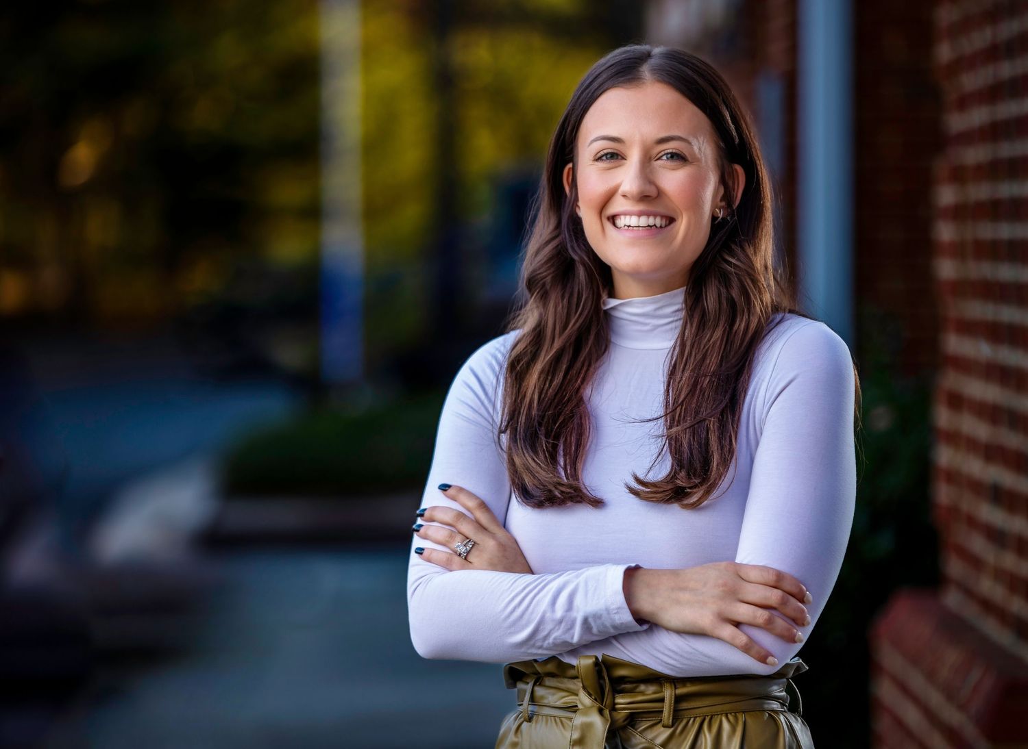 Woman in white top smiling outdoors in natural lighting.