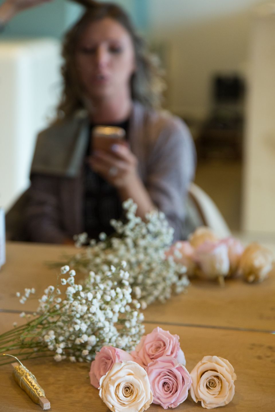 Pink roses and baby's breath flowers arranged on a wooden table with blurred background.