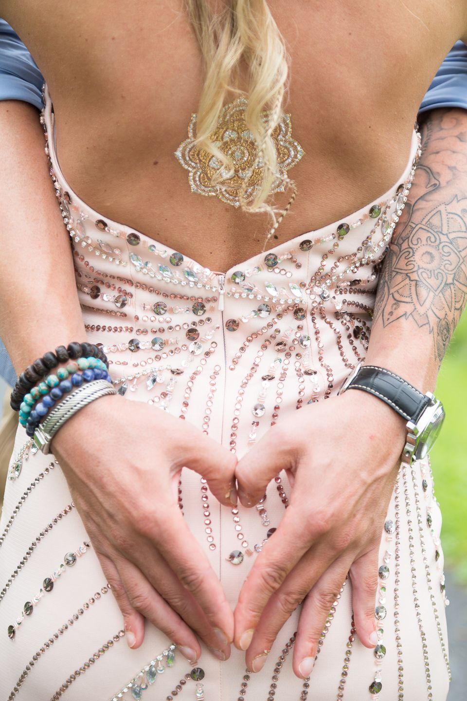 Heart shape made with hands against beaded wedding dress.