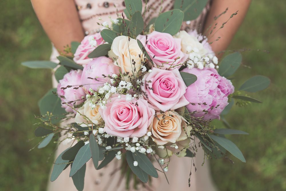 A beautiful bridal bouquet featuring pink roses, peonies and delicate greenery.