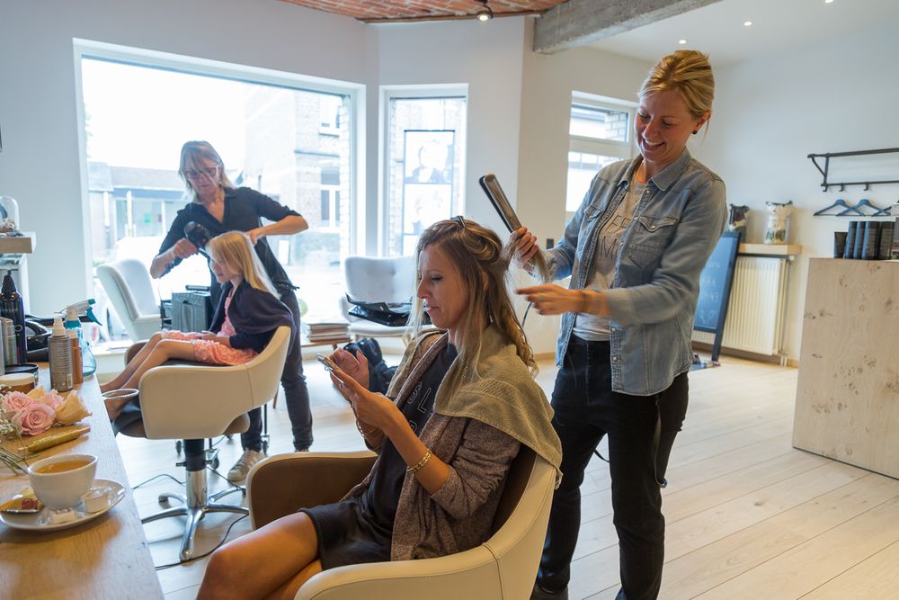 Stylists work on wedding day preparations in a modern salon setting.