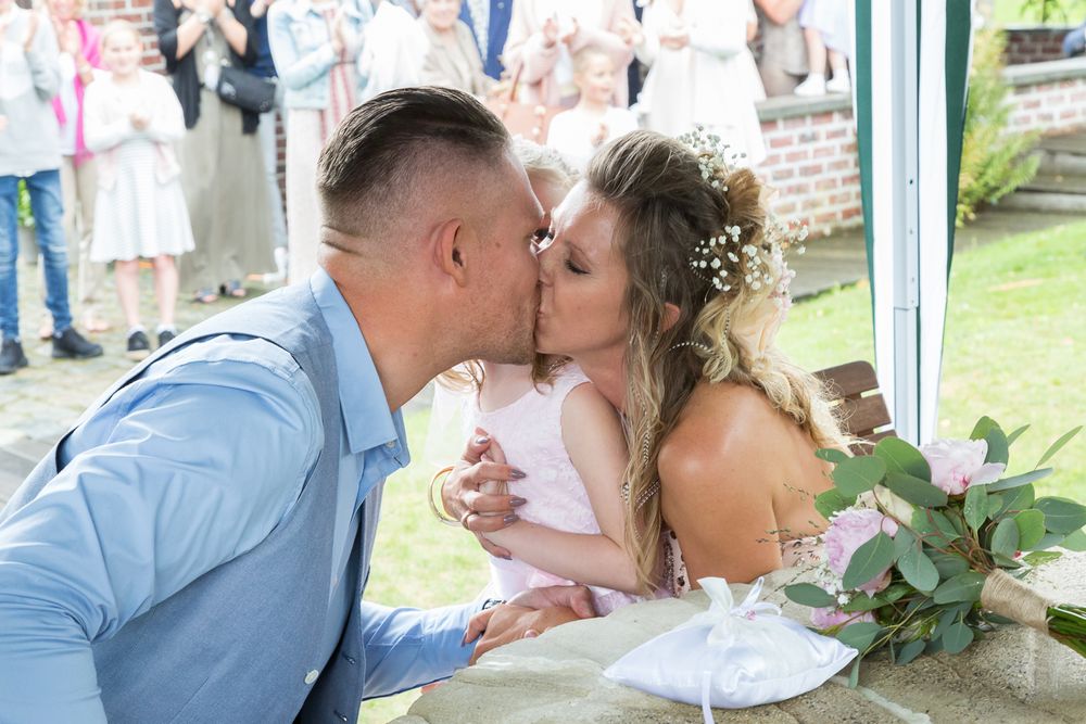 Romantic wedding day kiss shared by couple at outdoor ceremony.