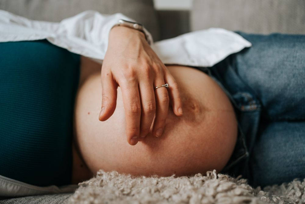 przyszła mama gładzi brzuszek - sesja domowa Kraków