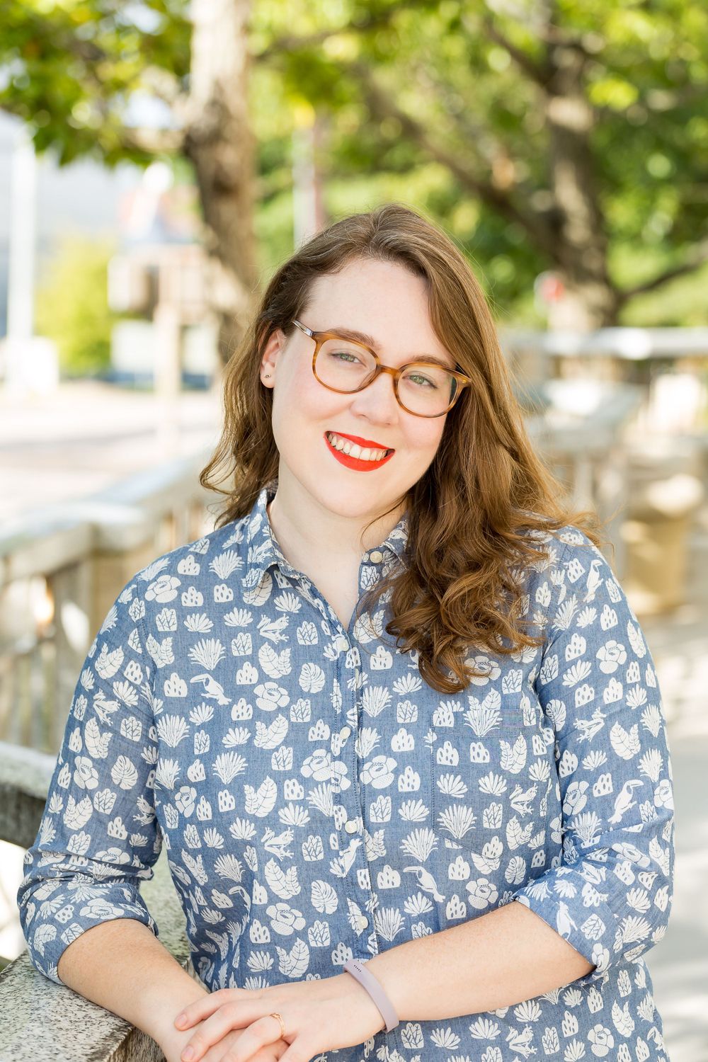 Outdoor portrait of person wearing glasses and floral print shirt with trees in background.