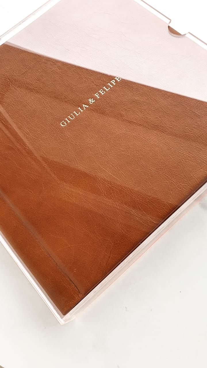 A brown leather photo album with 'GIULIA & FELIPE' embossed text on the cover.