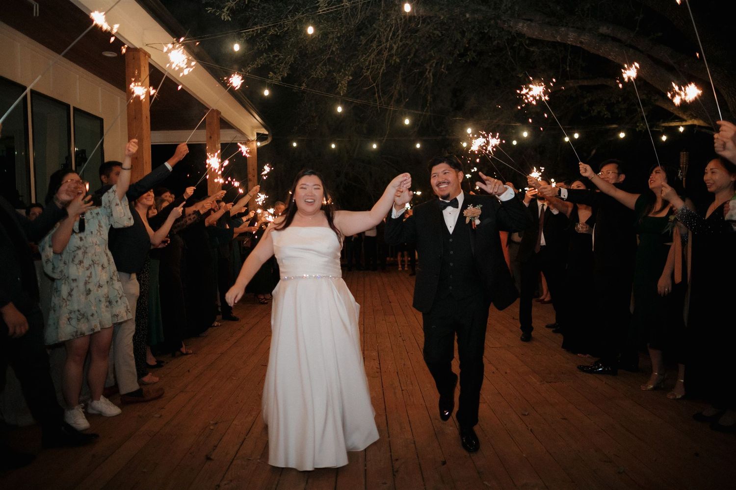Couple walks through sparkler exit tunnel surrounded by wedding guests.