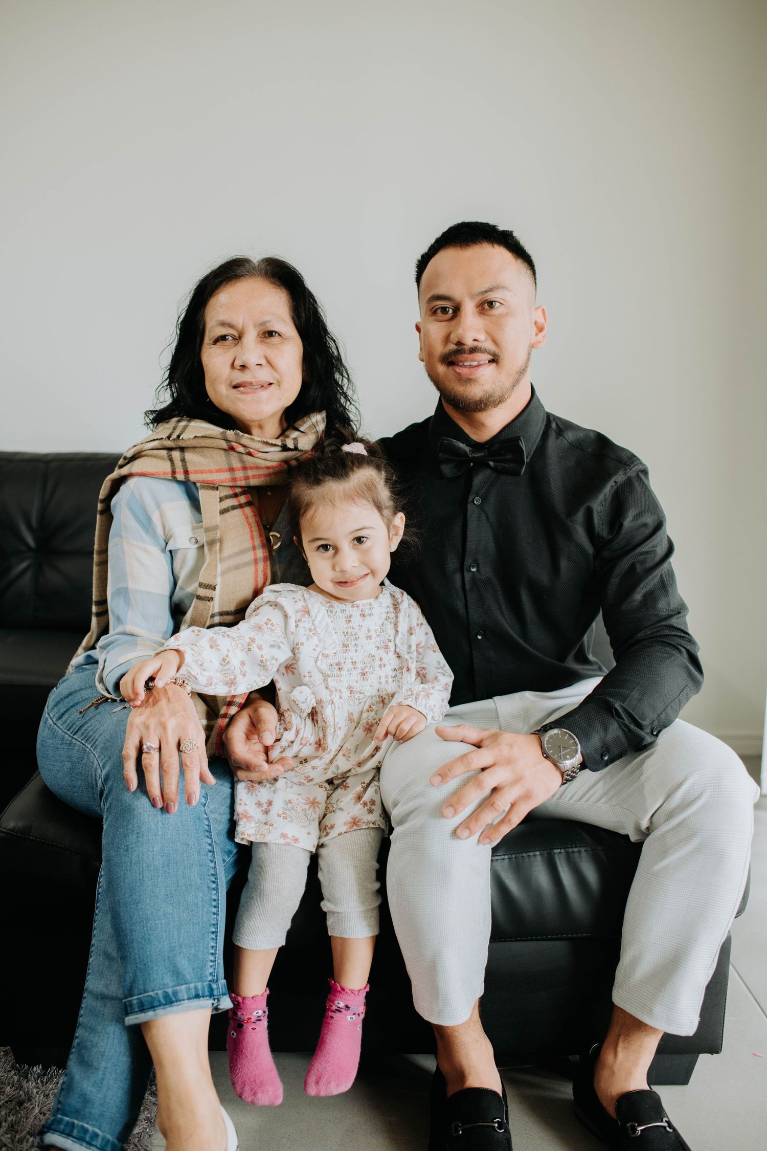 A family portrait on a leather couch in casual attire.