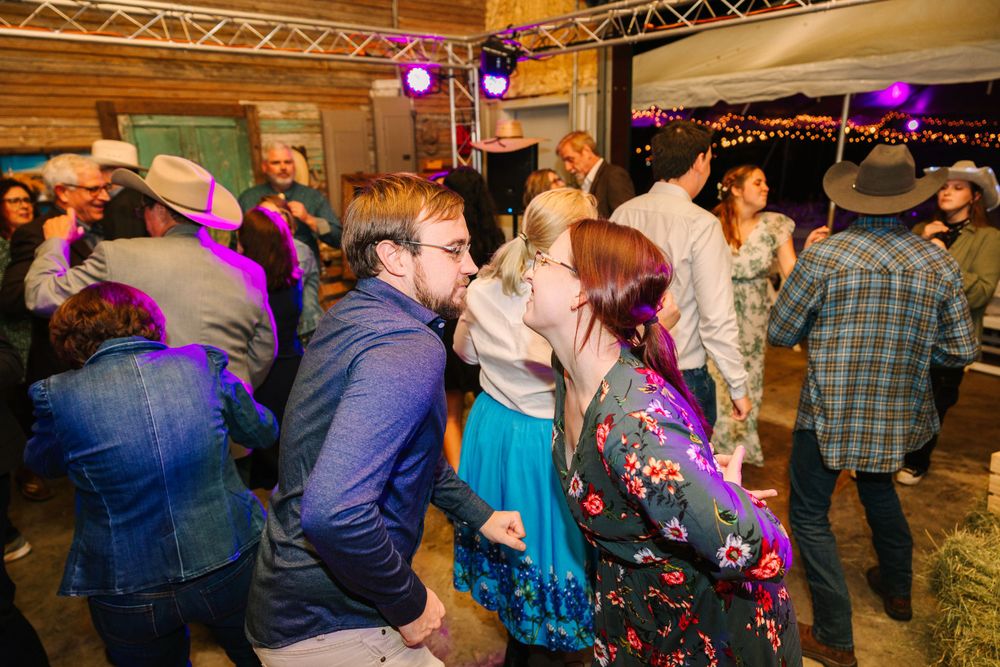 Crowded dance floor at a lively party with colorful lighting and people dancing in casual western attire.