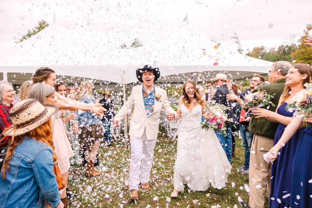 Wedding party celebrates with confetti toss during outdoor autumn ceremony.
