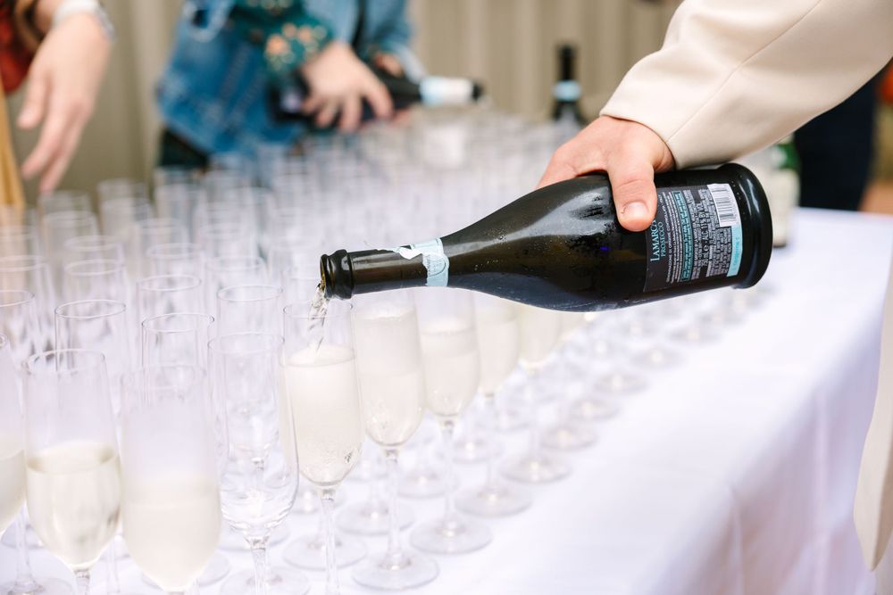 Someone pouring champagne into multiple glasses at an elegant event setup.