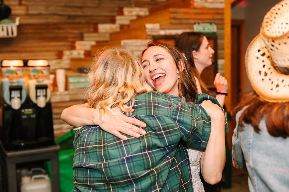 Two friends in plaid shirts sharing a joyful embrace while dancing at a party.
