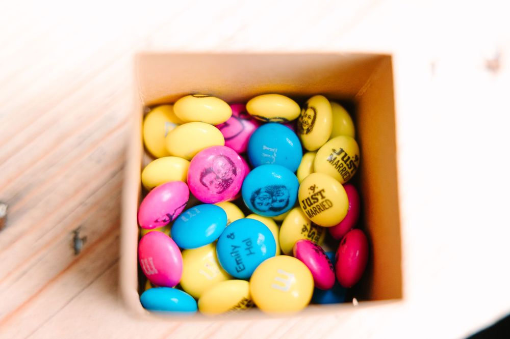 Colorful M&Ms candies in pink, yellow, and blue arranged in a small box.