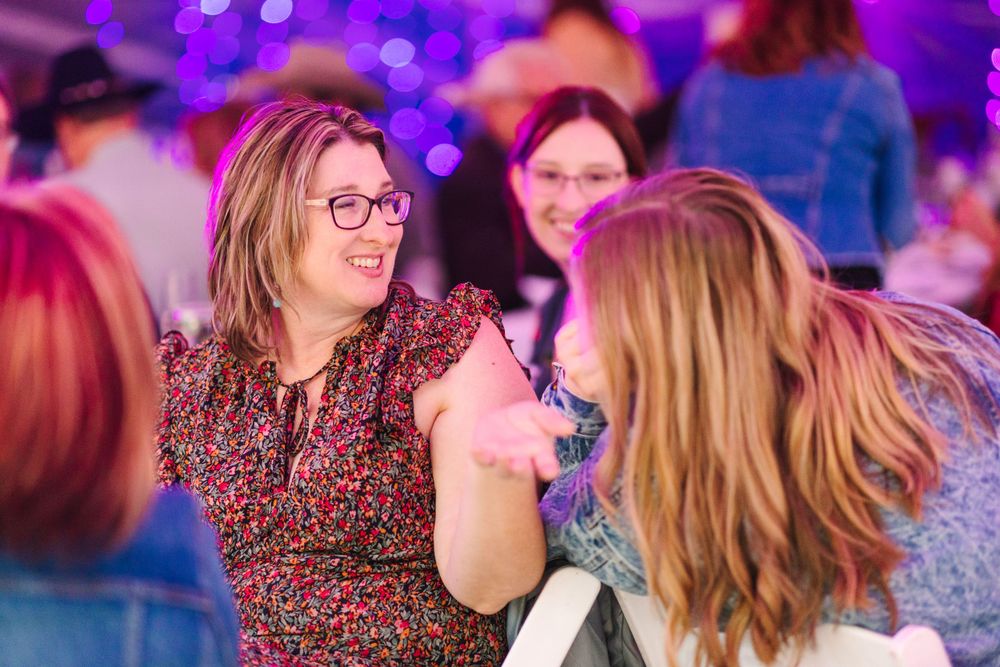 Wedding reception guests dancing and celebrating under purple mood lighting.