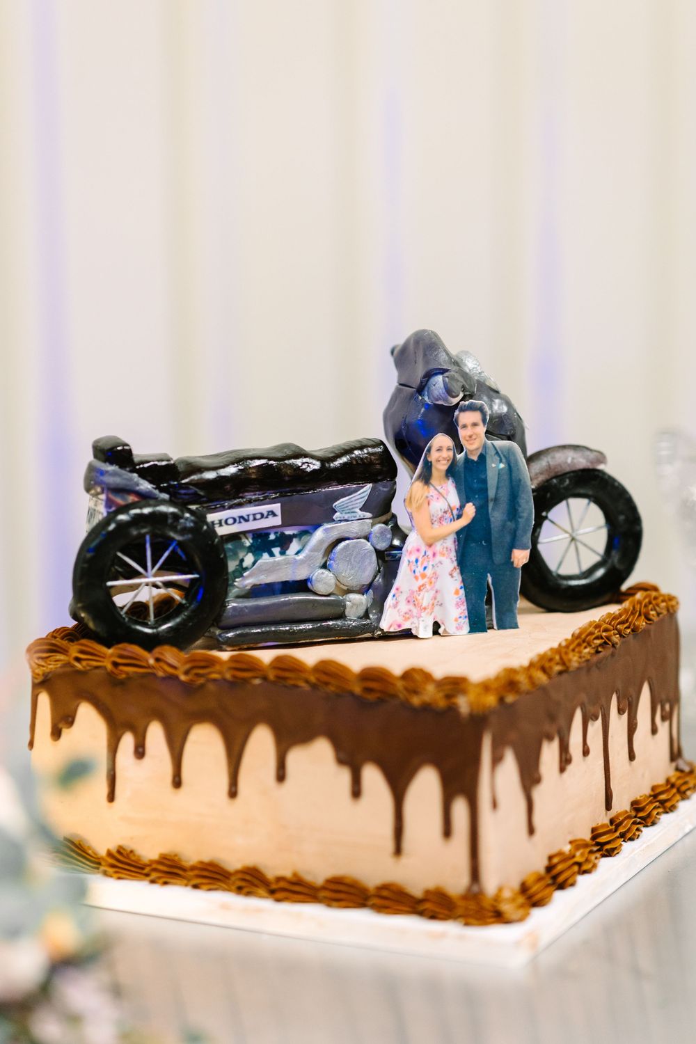 Chocolate drip wedding cake with motorcycle topper decoration.
