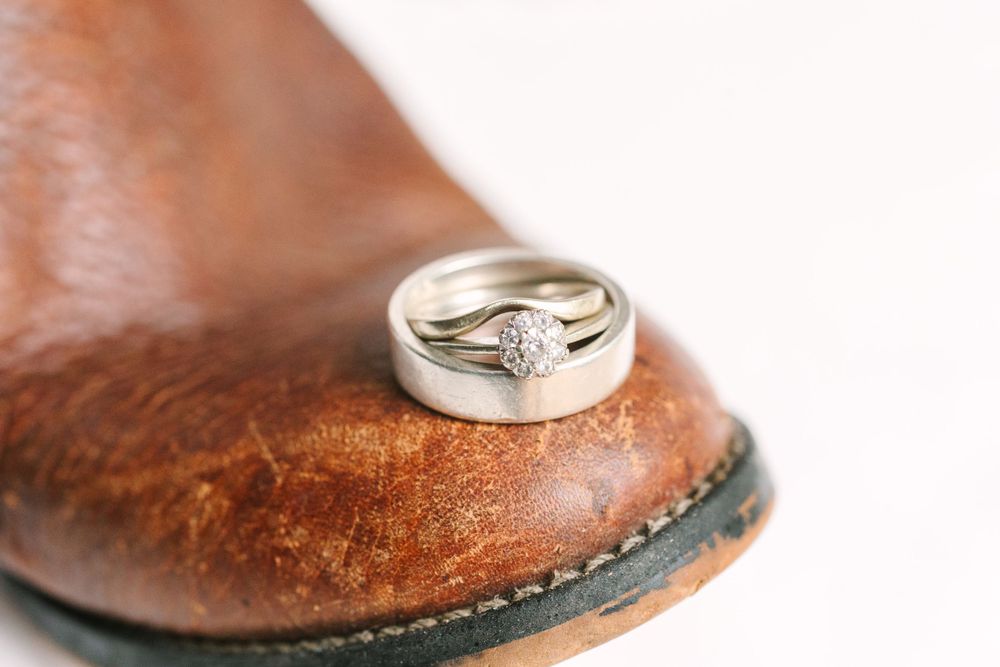 Diamond engagement ring displayed on brown leather with shallow depth of field.