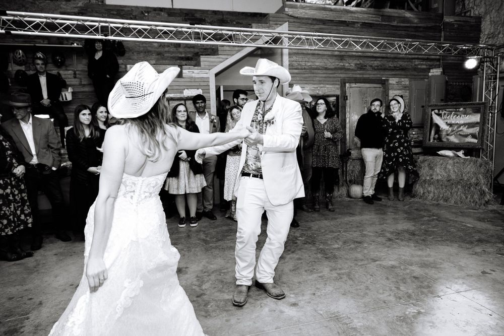 A black and white photo captures a couple dancing at their western-themed wedding reception.