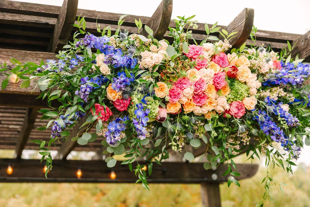 Close-up of vibrant pink and blue floral arrangement hanging from wooden pergola.
