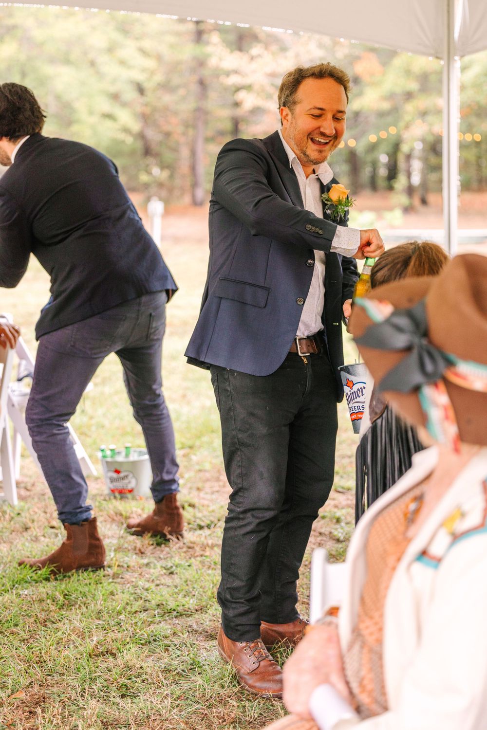 Guests dancing and celebrating at a casual outdoor wedding reception under a white tent.