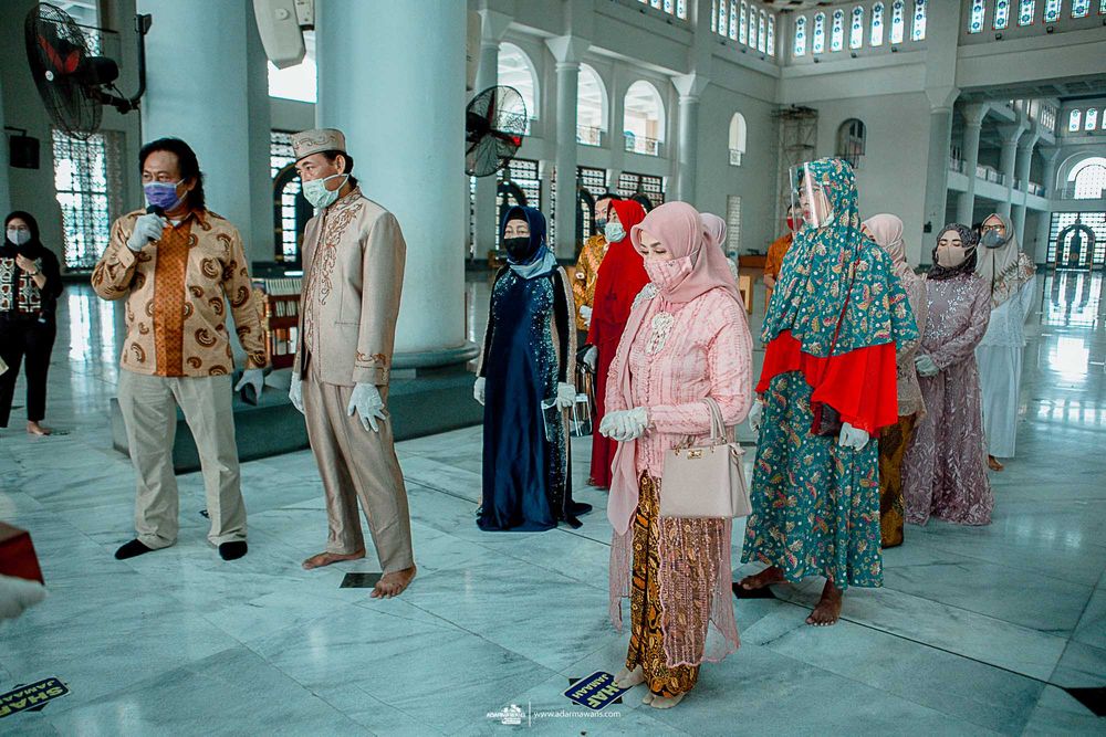Diverse group of mosque attendees in traditional clothing gathering in an ornate prayer hall.