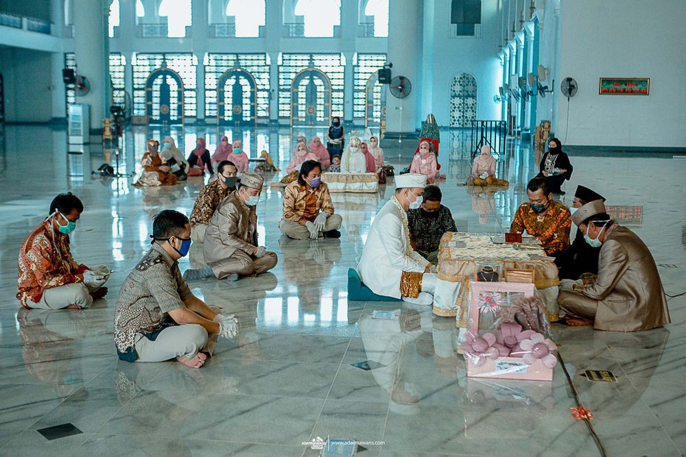 Large group of worshippers seated in circular formation on marble floor of modern mosque.