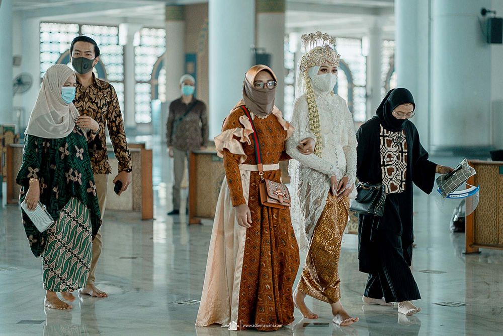 Women in traditional Islamic dress walking through modern mosque corridor.