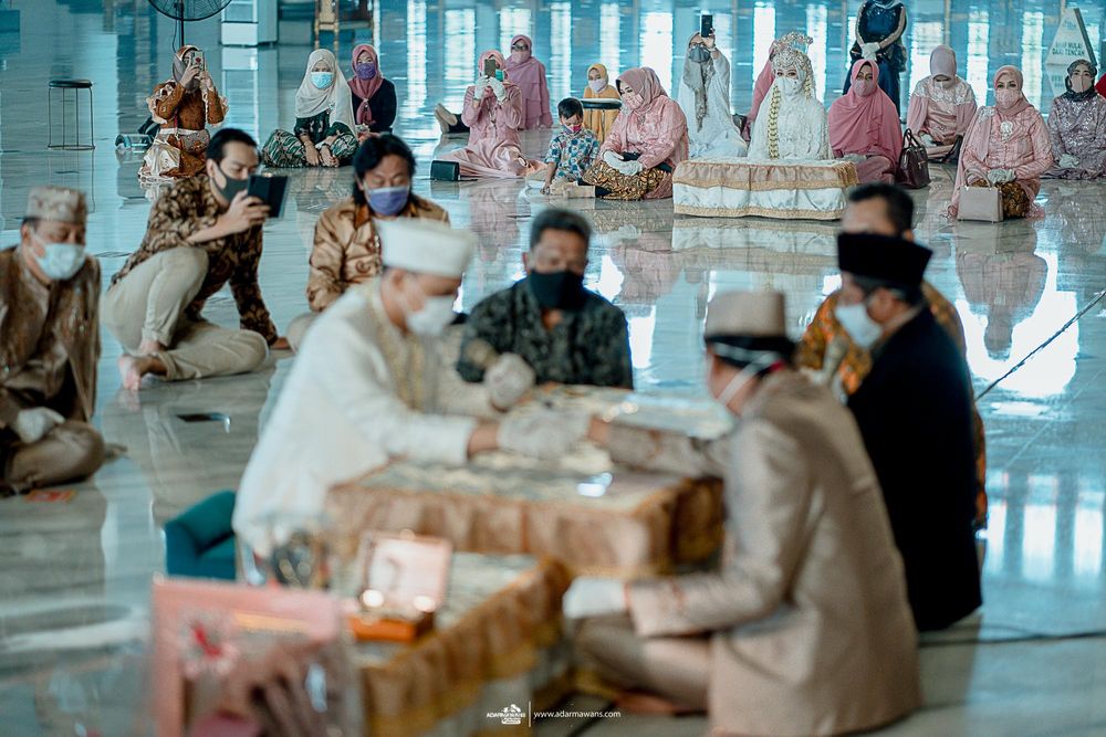People in traditional attire and masks gather in a large hall for a ceremony.