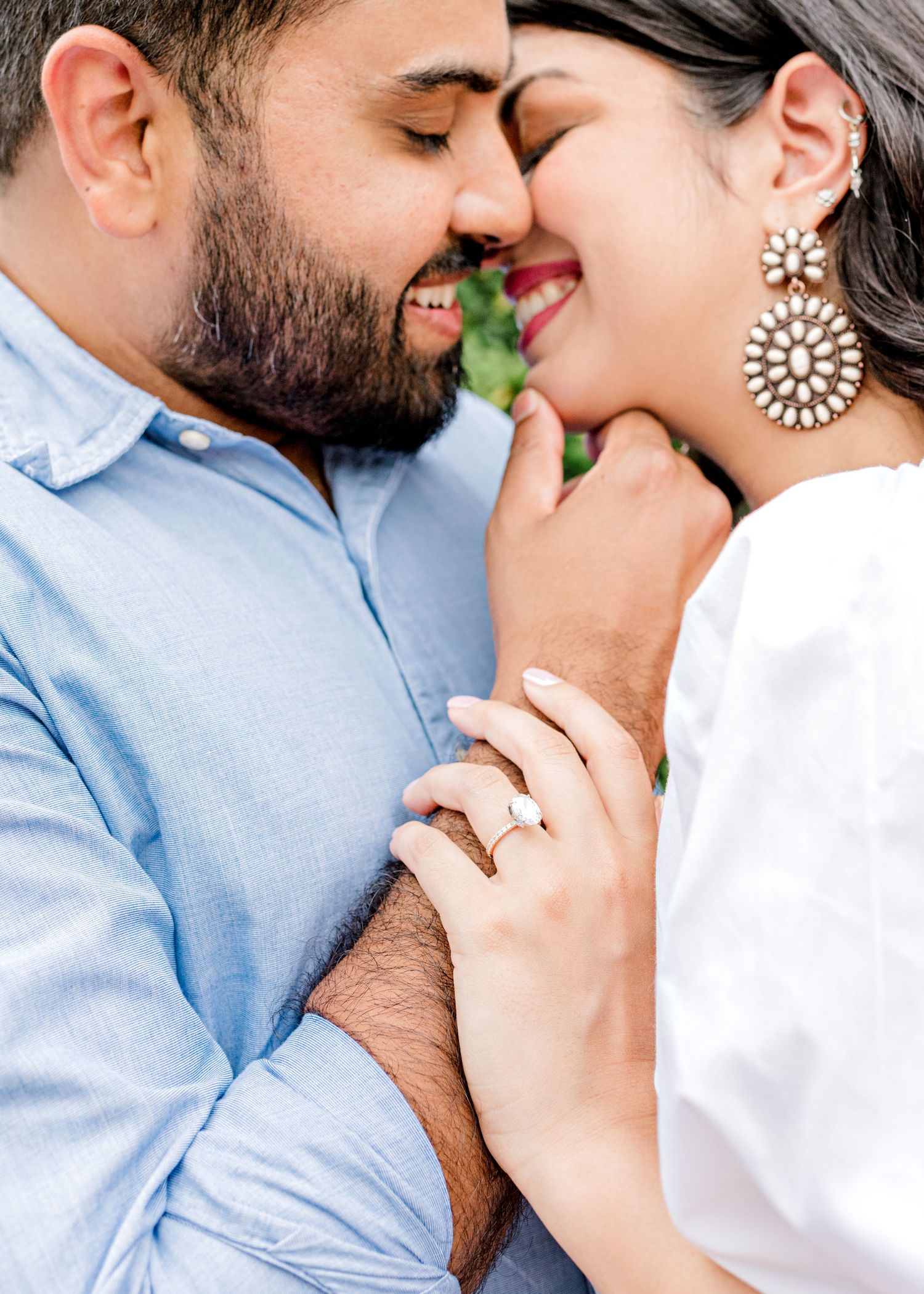Austin, TX engaged couple. guy's hand is putting girl's chin towards him, her hand resting on his arm, both smiling