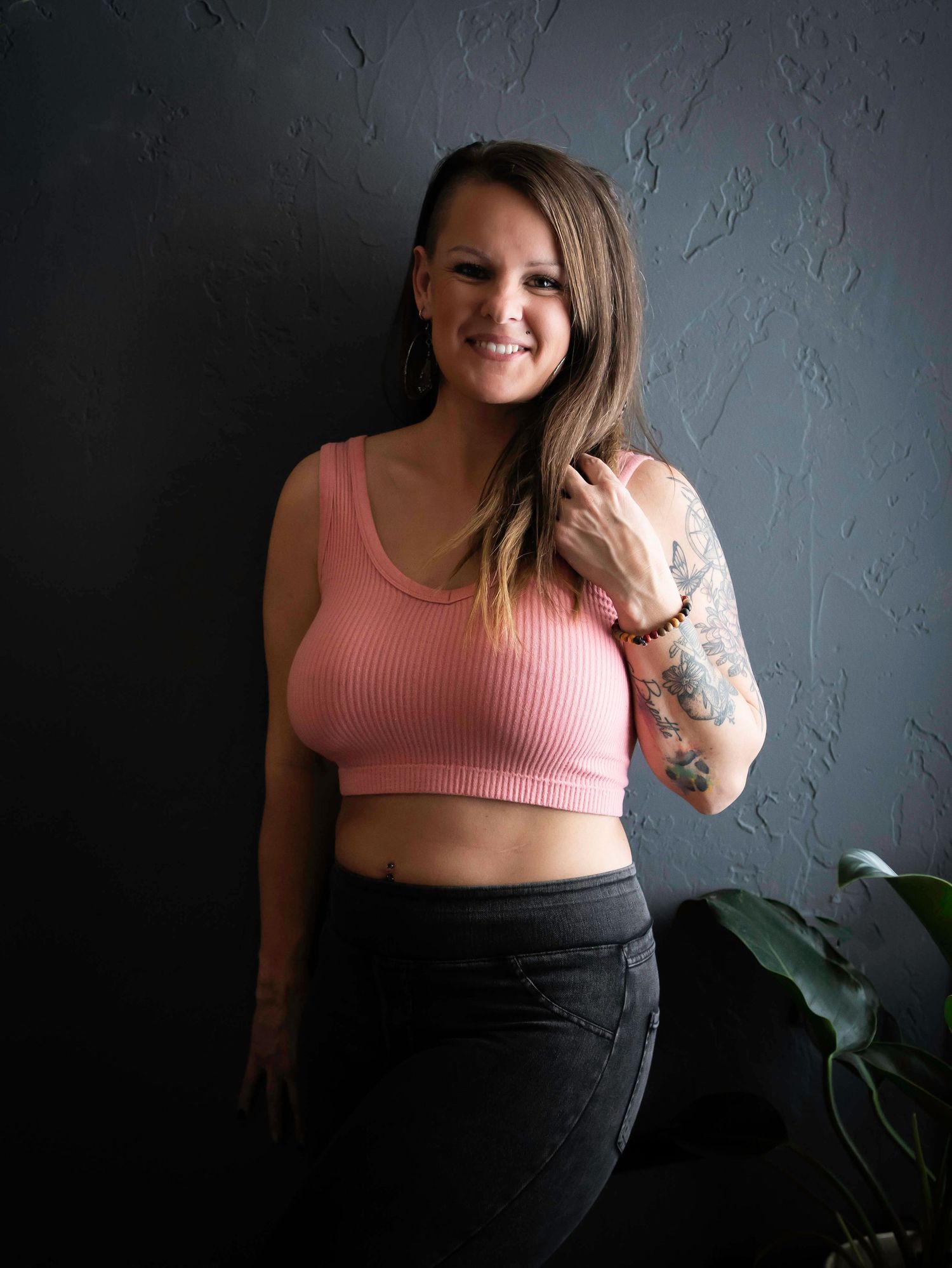 woman leaning against a grey wall with a pink shirt